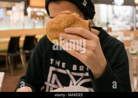 Young man eating hamburger Banque D'Images