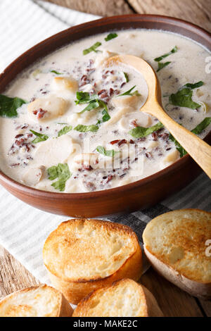 Soupe crémeuse du riz sauvage aux cèpes close-up dans un bol et des tartines sur la table verticale. Banque D'Images