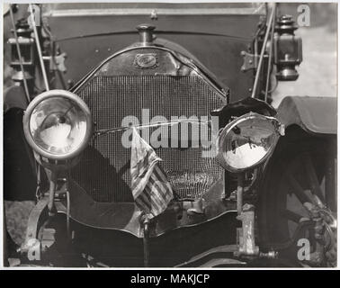 À l'horizontal, photographie en noir et blanc donnant une vue rapprochée d'un phare d'automobile endommagée et la grille. Phare droit de la voiture a été frappé hors de l'endroit, et la grille a une dent dans le coin inférieur droit. Un drapeau américain est suspendu à partir de la grille. Une petite plaque au-dessus de la grille se lit comme suit : "orris / St Louis.' pour un détail de la casse, des projecteurs voir P0054-00029. Titre : Close-up of a endommagé des projecteurs automobiles et grille. . Vers 1910. Holt, Charles Clement, 1866-1925 Banque D'Images