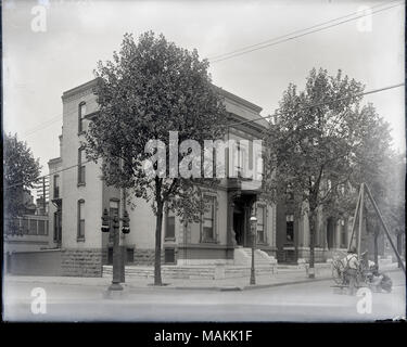 L'horizontale, 1970 Photographie noir et blanc montrant un quartier résidentiel de deux et trois étages de maisons en brique d'un bout à l'autre coin de rue. Au premier plan sur le côté droit, plusieurs hommes sont l'érection d'un lampadaire qui est suspendu sous une structure en bois. Un signe sur la structure lit ' l'approche la plus proche de la lumière naturelle. La lampe à arc de gaz.' Title : Installation du gaz lampes à arc à l'angle de Washington et Theresa Avenue. . Vers 1910. Banque D'Images