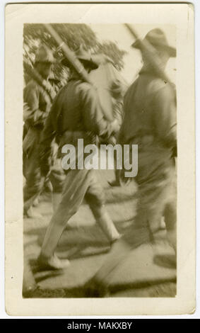 Photographie sépia, verticale montrant des soldats défilant dans une rangée tout en portant des fusils. L'un des soldats est à la recherche vers la caméra. Titre : Soldats en marche une ligne tout en portant des fusils. . Entre vers 1916 et vers 1918. Banque D'Images