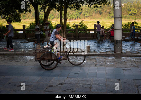 Yangshuo, Chine - 1 août 2012 : scène de rue dans la ville de Yangshuo avec une femme et un garçon en vélo, en Chine. Banque D'Images