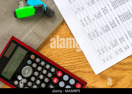 Close-up de l'espace de travail comme comptable mise à plat du dessus avec la paperasse et les documents avec les chiffres dans les tableaux et graphiques et calculatrice avec retour en bois Banque D'Images