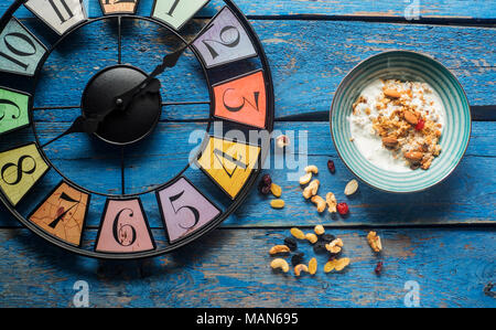 Horloge style vintage, bol à céréales sur table planche peinte en bleu Banque D'Images