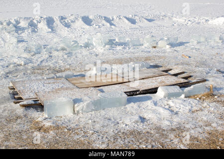 Le trou dans la glace fermés par des planches, des morceaux de glace Banque D'Images