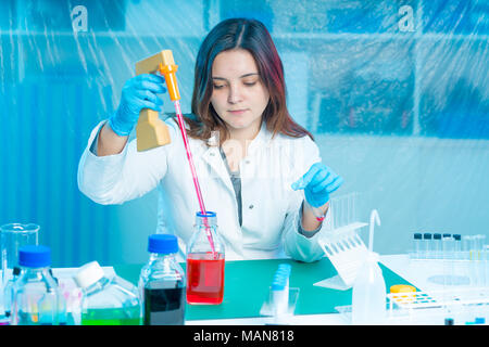 Jeune femme technicien utilise une pipette dans un laboratoire chimique Banque D'Images