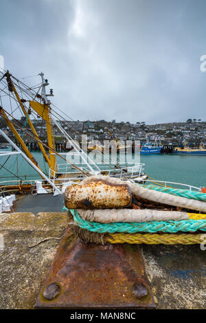 Cordes liées à un vieux rusty corrodés bollard à côté de chalutiers de pêche dans le port de la cornish fishingh ville ou village de pêche cornsih newlyn. Banque D'Images