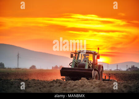 Tracteur avec poignées cultivateur champ avant la plantation, sunset shot Banque D'Images