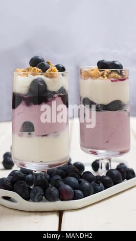 Parfait de granola et yogourt aux bleuets dans deux grands verres sur fond bleu Banque D'Images