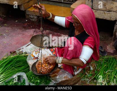 Personnes âgées femme indienne vend des fruits et légumes portant de nombreux bracelets blancs sur ses bras pour encourager la vie de son mari l'Inde Jaisalmer Banque D'Images