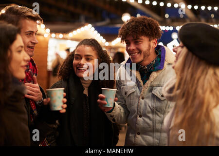 Groupe d'Amis de boire du vin chaud au marché de Noël Banque D'Images