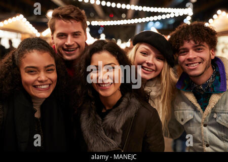 Jeunes amis qui pose pour le marché de Noël à Selfies Banque D'Images