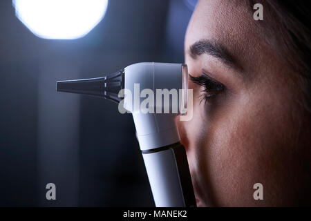 Femme médecin à l'aide d'un otoscope pour examen, side view Banque D'Images