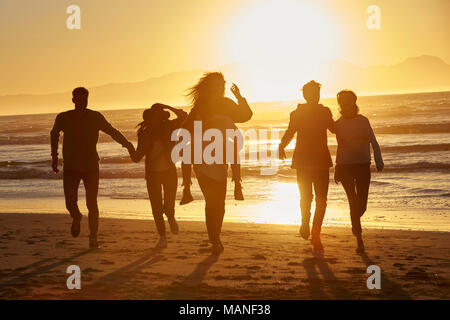 Silhouette d'amis s'amuser le long de la plage d'hiver Banque D'Images