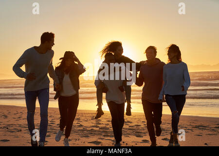 Silhouette d'amis s'amuser le long de la plage d'hiver Banque D'Images