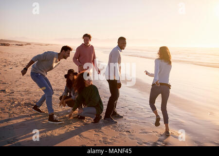 Amis jouant et des zéros traverse dans le sable sur la plage d'hiver Banque D'Images