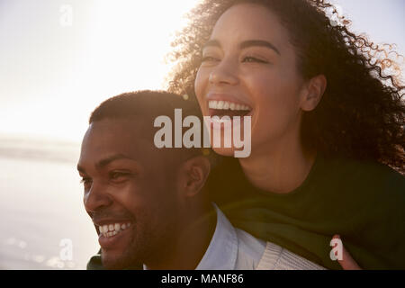 Man Giving Woman Piggyback sur Winter Beach Locations Banque D'Images