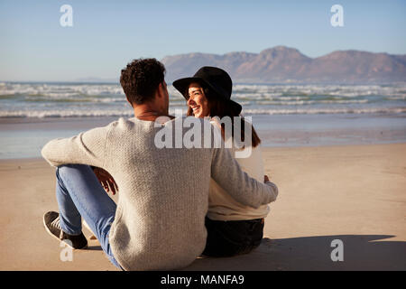 Couple assis sur une plage d'hiver Ensemble Banque D'Images