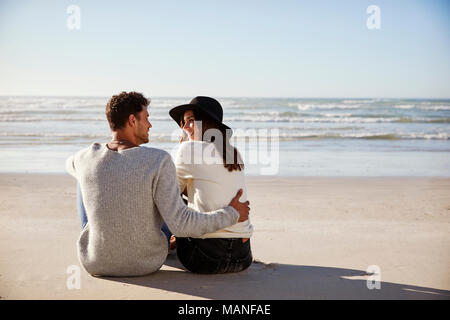 Couple assis sur une plage d'hiver Ensemble Banque D'Images