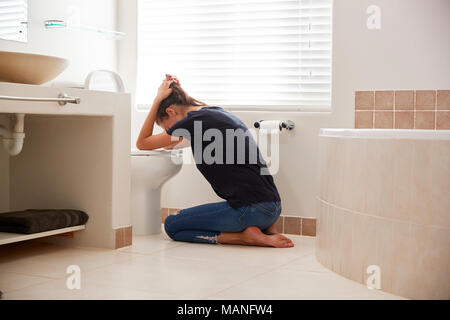 Femme souffrant de maladie de matin dans la salle de bains à la maison Banque D'Images