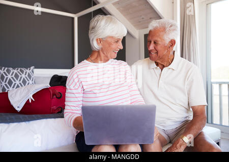 Senior Couple Regardez comme ils l'ordinateur portable à l'Hôtel de maison de vacances Banque D'Images