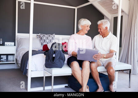 Senior Couple Regardez comme ils l'ordinateur portable à l'Hôtel de maison de vacances Banque D'Images