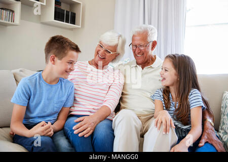 Portrait de petits-enfants assis sur un canapé avec les grands-parents Banque D'Images