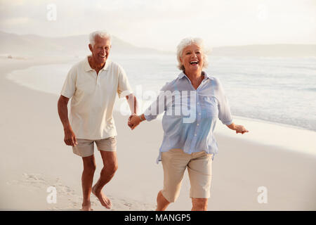 Couple de retraités Senior Le Long Beach Main dans la main Ensemble Banque D'Images