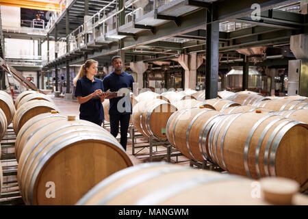 Deux membres du personnel de l'inspection des barils de vin dans un entrepôt d'usine Banque D'Images