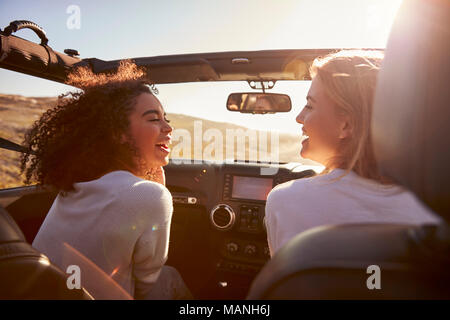 Deux copines de la conduite avec le toit ouvert regarder les uns les autres Banque D'Images