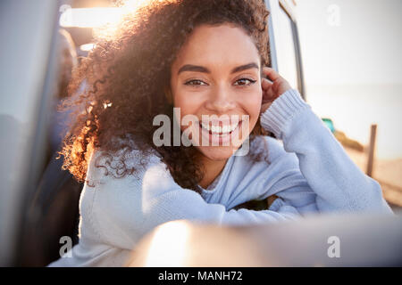 Young woman leaning on fenêtre ouverte de la voiture à la recherche à l'appareil photo Banque D'Images