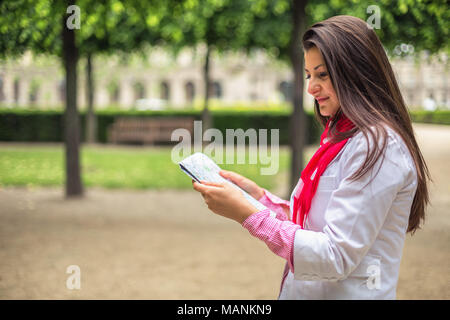 Confus young girl holding Plans de ville en jardin des Tuileries, Paris, France Banque D'Images