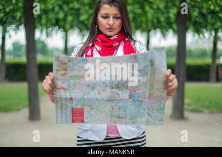 Confus young girl holding Plans de ville en jardin des Tuileries, Paris, France Banque D'Images