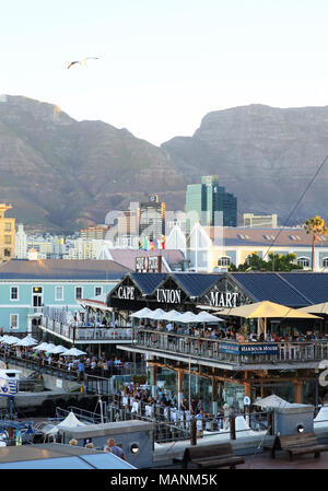 Les personnes mangeant dans des restaurants donnant sur le front de mer V&A, au crépuscule, à Cape Town, capitale de l'Afrique du Sud Banque D'Images