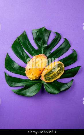 Mise en page créative faite de l'été fruits tropicaux et tropicaux feuilles sur fond violet. Mise à plat. Concept alimentaire. Concept Tropical. Banque D'Images