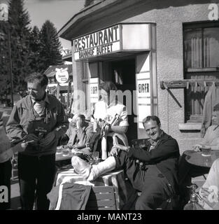 1957, Suisse, historique, pour les amateurs de détente, assis devant le restaurant Eiger, Bahnhof, Wengen. Un des hommes a la jambe dans le plâtre. Banque D'Images