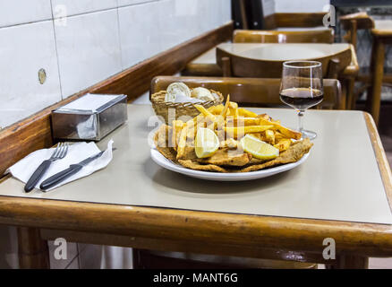 Une plaque d'Milanesas con papas fritas (schnitzel faite avec des pommes de terre frites et viande de vache) sur une table en bois dans un petit restaurant pour les travailleurs à Buenos Banque D'Images