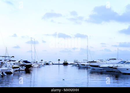 Port de plaisance dans la soirée avec de luxueux voiliers et bateaux à moteur à l'ancre. Scène Marina dans le coucher du soleil. Banque D'Images