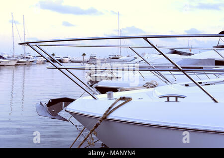 Port de plaisance dans la soirée avec de luxueux voiliers et bateaux à moteur à l'ancre. Scène Marina dans le coucher du soleil. Banque D'Images