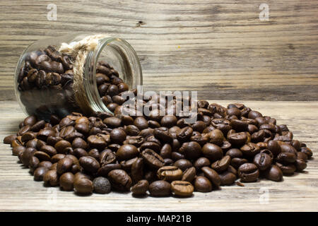 Grains de café dans un bocal en verre sur fond de bois Banque D'Images