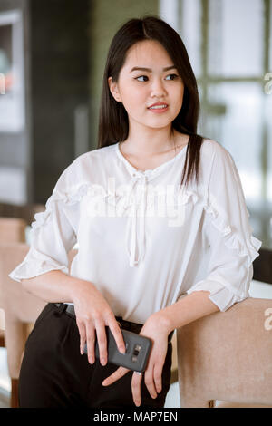 Femme Asiatique avec des cheveux long noir noir droit portant blouse blanche Banque D'Images