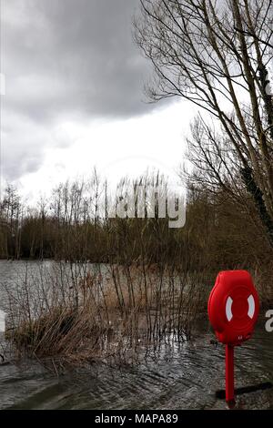Une bouée dans une case rouge lumineux donnant sur un lac dans le Suffolk inondées Needham UK Banque D'Images