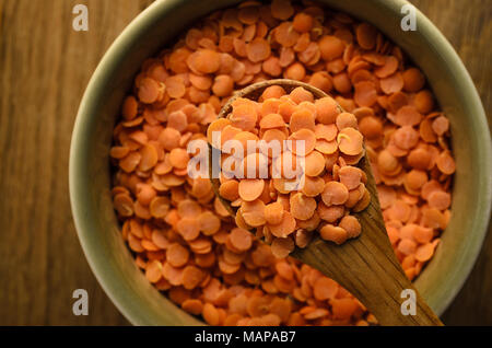 Passage libre d3 cuillère en bois levée de plus green bol rempli avec des lentilles rouges sur table en chêne. Banque D'Images
