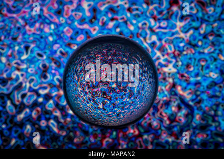 Boule en verre clair avec des motifs de couleur de la lumière reflétée en elle. Banque D'Images