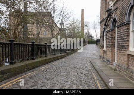 Moulin à sel, la cheminée de Victoria Mills et une rue pavée de la Victorian village modèle de Saltaire Yorkshire Banque D'Images