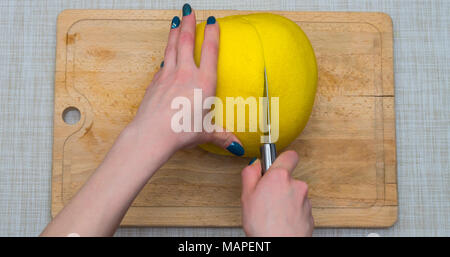 Girl cleaning ses mains avec agrumes pomelo, sur une planche en bois Banque D'Images