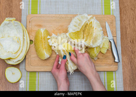 Girl cleaning ses mains avec agrumes pomelo, sur une planche en bois Banque D'Images