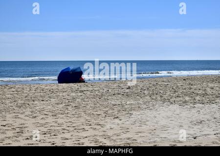 Deux personnes assises sur la plage vide avec des parasols à Ocean City, MD, États-Unis d'Amérique Banque D'Images