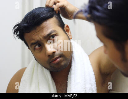 Recherche homme asiatique indien après sa comparution devant un miroir beauté coiffants Coiffants.vie Banque D'Images