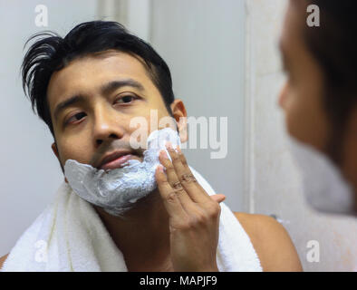 Homme lookingIndian asian après son apparition en face d'un miroir style beauté VIE. Routine de rasage mousse application Banque D'Images